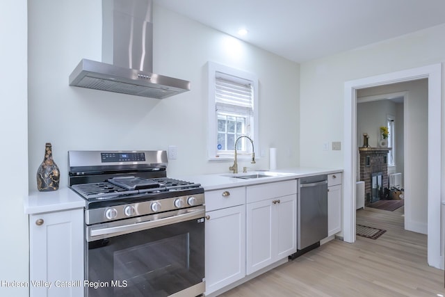 179 Grove St, Tillson, NY 12486 - kitchen with appliances with stainless steel finishes, wall chimney range hood, a sink, white cabinets, and light countertops