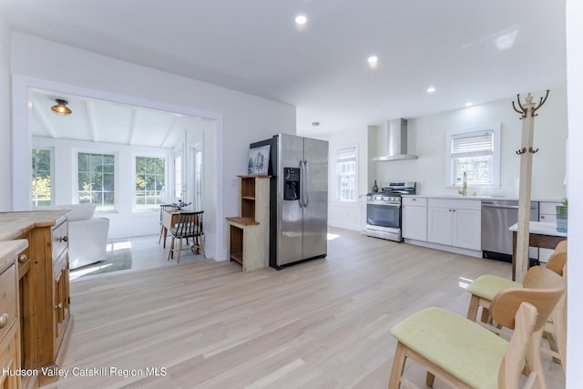 kitchen featuring a wealth of natural light, wall chimney exhaust hood, lofted ceiling with beams, and appliances with stainless steel finishes