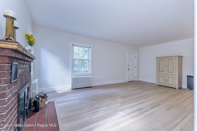 unfurnished living room with a fireplace, radiator heating unit, and light hardwood / wood-style flooring