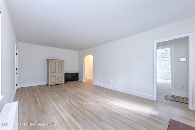 179 Grove St, Tillson, NY 12486 - unfurnished living room with arched walkways, light wood-type flooring, and baseboards