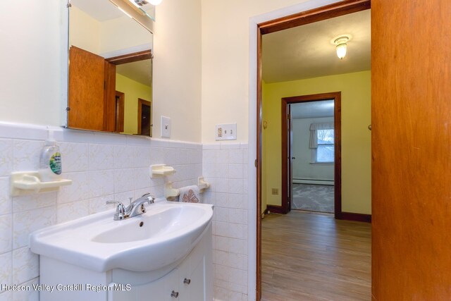 bathroom with vanity, wood-type flooring, tile walls, and a baseboard heating unit