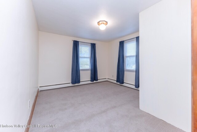 unfurnished room with light colored carpet and a baseboard heating unit