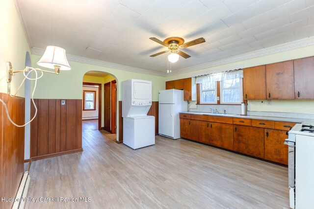 kitchen featuring sink, stacked washer / dryer, crown molding, light hardwood / wood-style floors, and white appliances