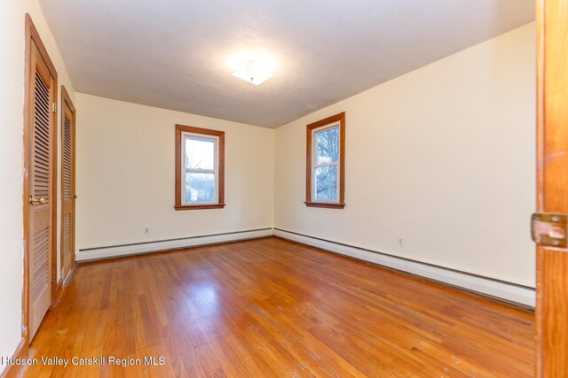 unfurnished bedroom featuring wood-type flooring and baseboard heating