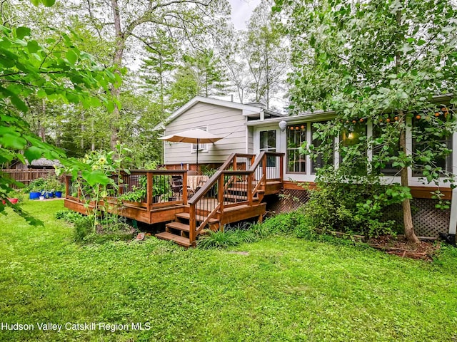 rear view of property with a sunroom, a lawn, and a wooden deck