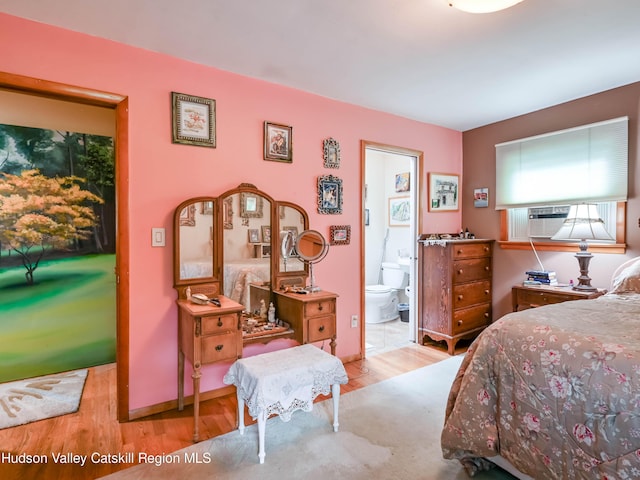 bedroom with connected bathroom, light hardwood / wood-style floors, and cooling unit