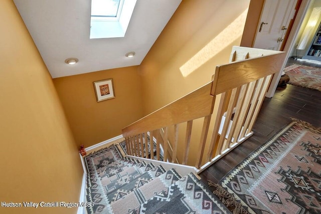 staircase with hardwood / wood-style floors and a skylight