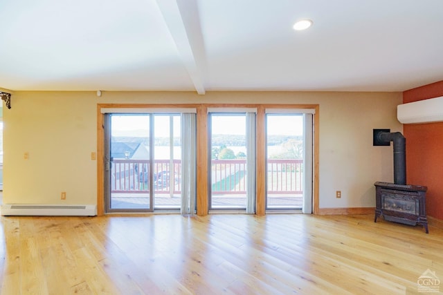 38 Cheviot Rd Unit 8, Germantown, NY 12526 - unfurnished living room with a baseboard radiator, a wood stove, a wall mounted AC, wood finished floors, and recessed lighting