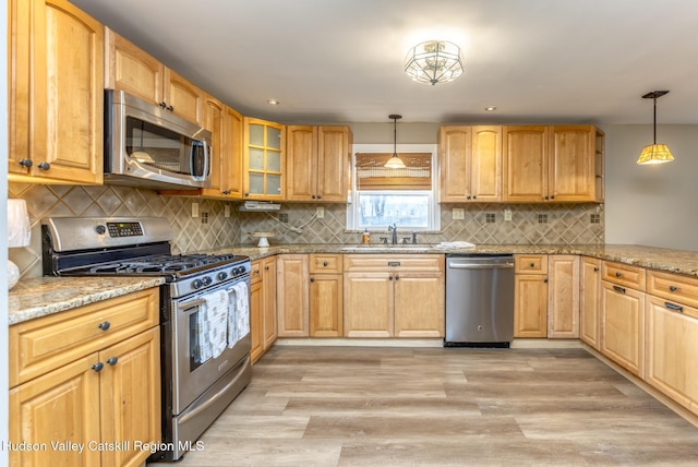 kitchen with pendant lighting, sink, light hardwood / wood-style flooring, appliances with stainless steel finishes, and light stone counters