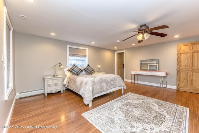 bedroom with hardwood / wood-style floors, a baseboard radiator, and ceiling fan