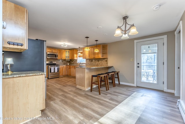 kitchen with hanging light fixtures, a kitchen breakfast bar, stainless steel appliances, tasteful backsplash, and kitchen peninsula