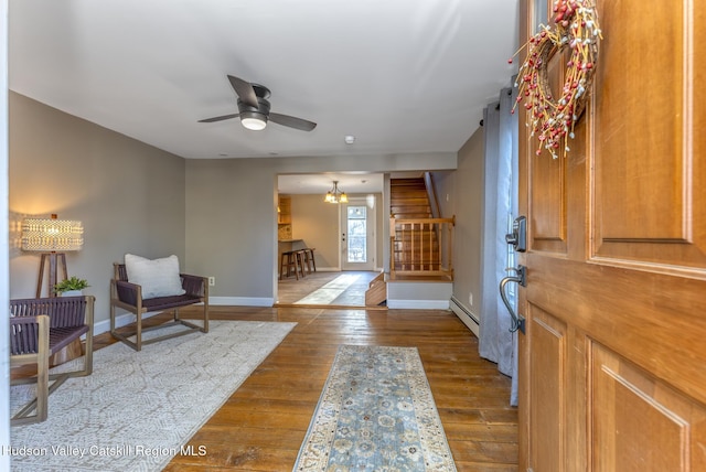 foyer entrance featuring wood-type flooring, ceiling fan with notable chandelier, and baseboard heating