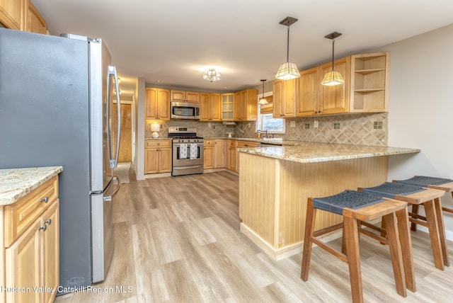 kitchen with pendant lighting, light stone counters, stainless steel appliances, and kitchen peninsula