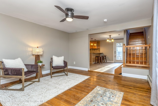 living area with wood-type flooring, ceiling fan with notable chandelier, and a baseboard radiator