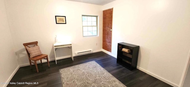 living area with dark hardwood / wood-style flooring and a baseboard heating unit