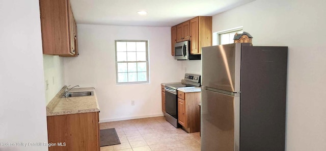 kitchen featuring light tile patterned floors, stainless steel appliances, plenty of natural light, and sink