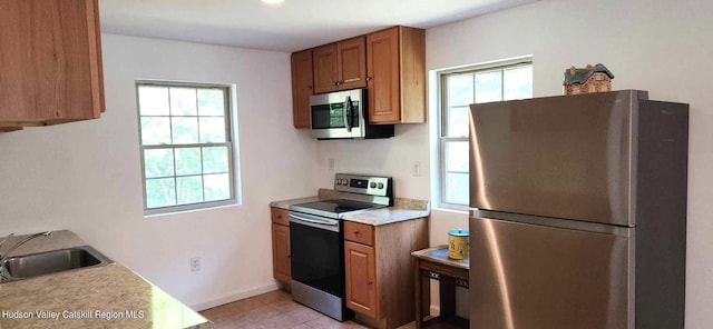 kitchen featuring a healthy amount of sunlight, sink, light tile patterned flooring, and stainless steel appliances