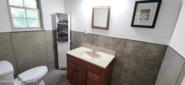 bathroom with vanity, toilet, and tile walls