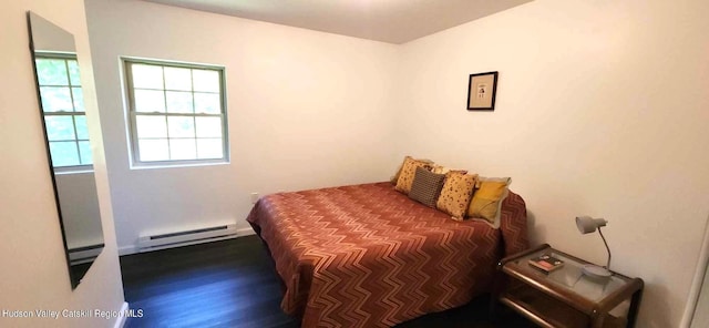 bedroom with dark hardwood / wood-style floors and a baseboard heating unit