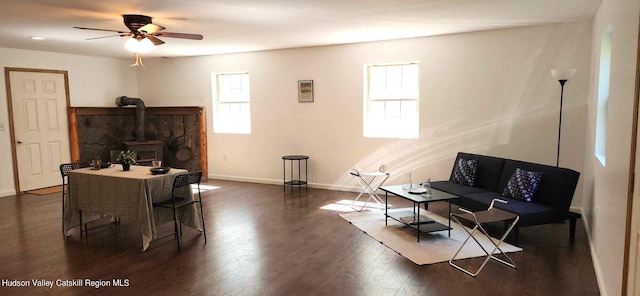 living room featuring a wood stove, a wealth of natural light, dark wood-type flooring, and ceiling fan