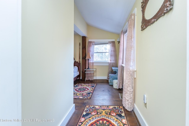 corridor with vaulted ceiling and dark hardwood / wood-style floors