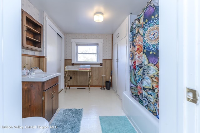 full bathroom with vanity, toilet, shower / bathtub combination with curtain, and wooden walls