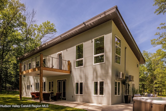 back of house with a balcony, a patio area, and a hot tub