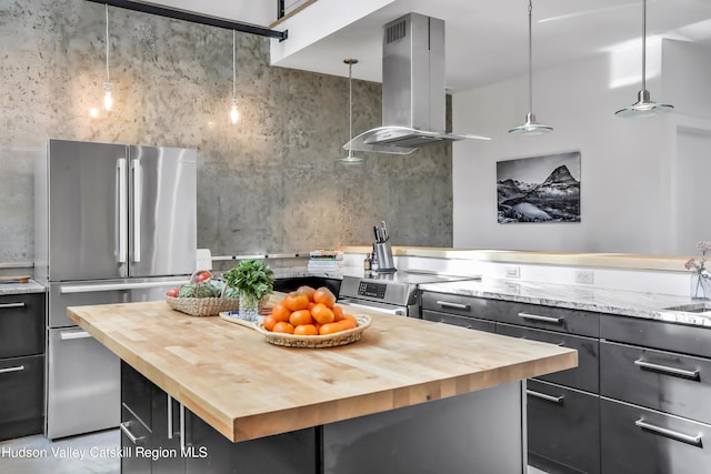 kitchen featuring appliances with stainless steel finishes, wood counters, decorative light fixtures, a kitchen island, and island range hood