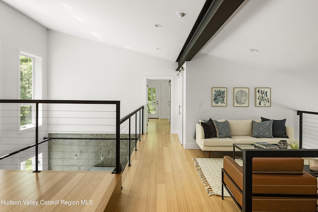 living room featuring a barn door, light hardwood / wood-style flooring, and lofted ceiling with beams