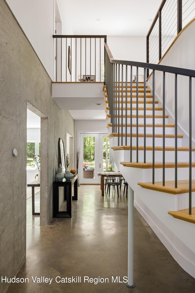 stairs with french doors and concrete floors