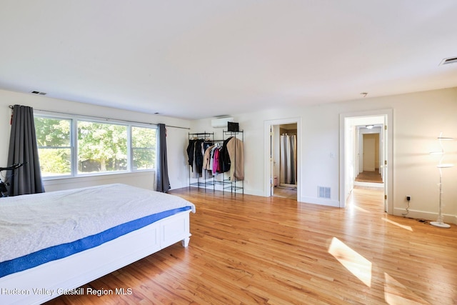 bedroom featuring light wood-type flooring and a wall mounted AC