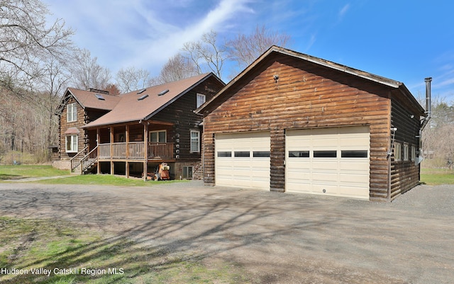 log home featuring covered porch and a garage