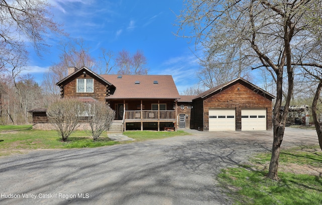 cabin with a front yard, a porch, and a garage