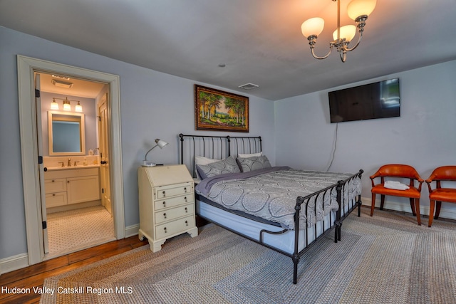 bedroom with sink, hardwood / wood-style flooring, a notable chandelier, and ensuite bathroom