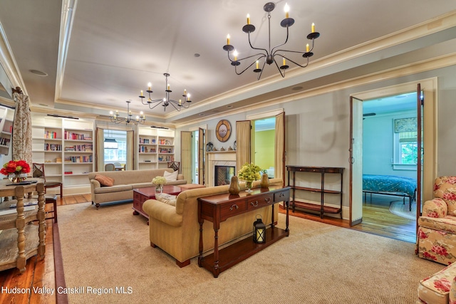 living room featuring a tray ceiling, hardwood / wood-style floors, ornamental molding, and an inviting chandelier