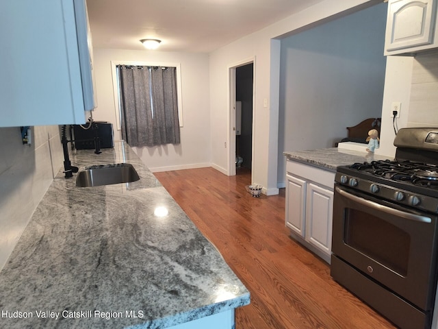 kitchen with blue cabinets, dark wood-type flooring, sink, white cabinets, and stainless steel range with gas stovetop