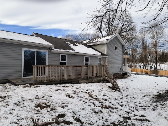 snow covered back of property featuring a deck