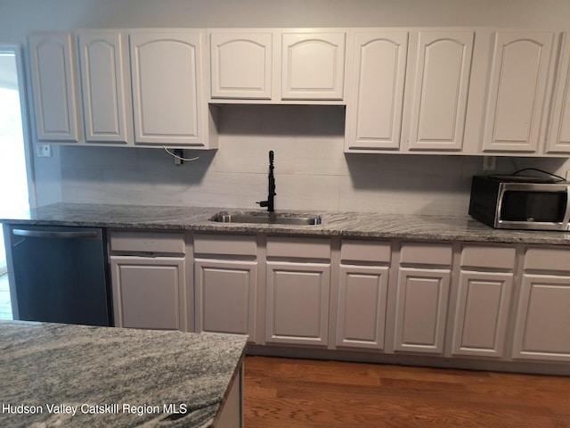 kitchen with dark wood-type flooring, dark stone counters, white cabinets, sink, and stainless steel appliances