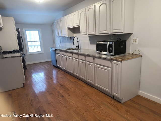 kitchen with appliances with stainless steel finishes, dark wood-type flooring, sink, white cabinets, and lofted ceiling