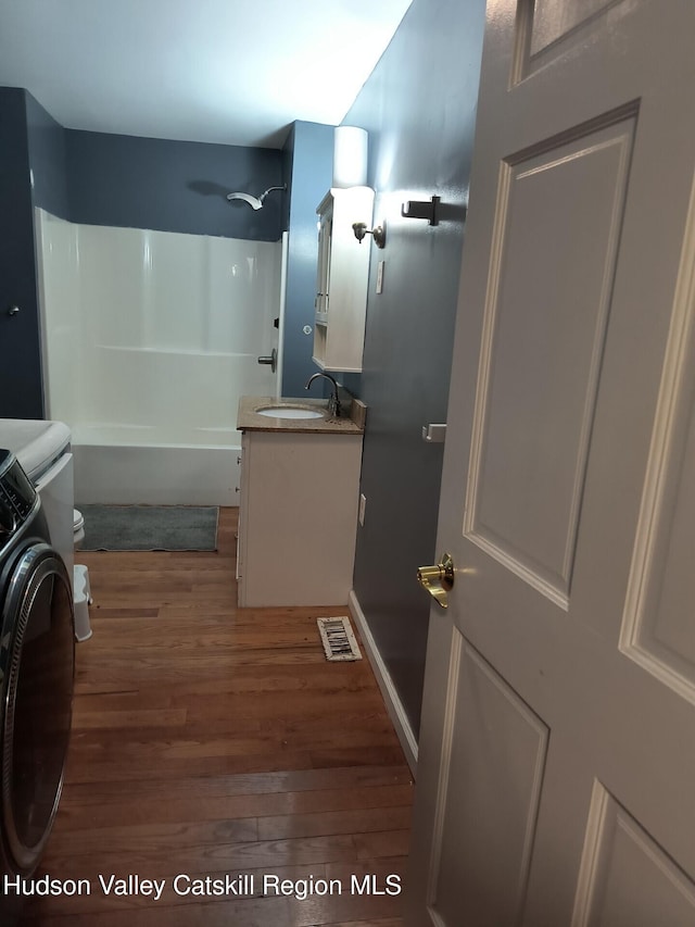 full bathroom with vanity, hardwood / wood-style flooring, toilet, tub / shower combination, and washer / clothes dryer