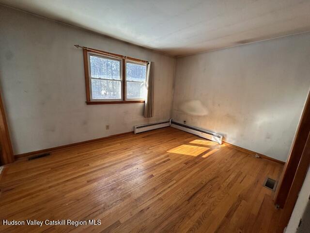 unfurnished room with a baseboard radiator and light hardwood / wood-style floors