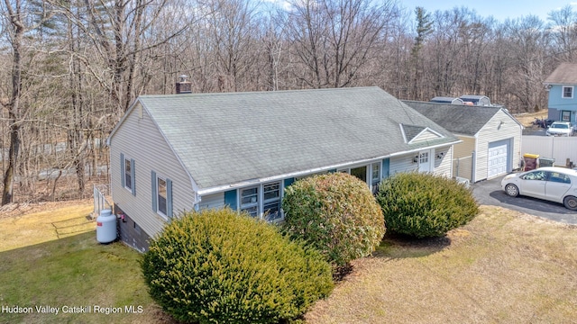 exterior space with a front yard, a chimney, roof with shingles, and aphalt driveway