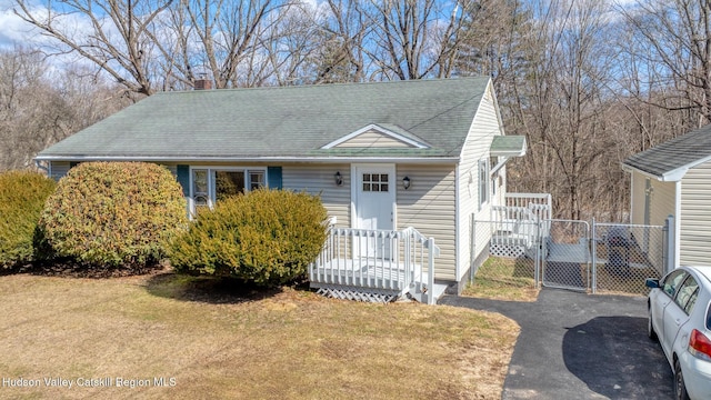 view of front of home featuring a front yard, a gate, fence, driveway, and roof with shingles