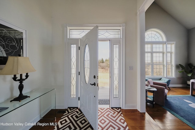 entryway featuring lofted ceiling, dark wood-type flooring, and baseboards