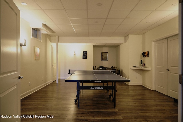 game room with a drop ceiling, dark wood finished floors, and baseboards