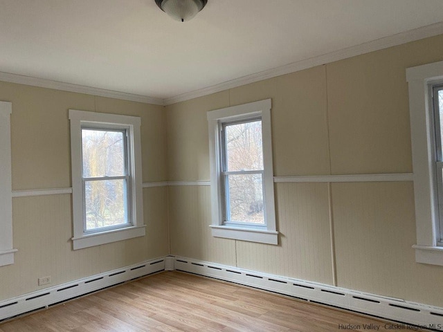 empty room with baseboard heating, crown molding, and light wood-type flooring