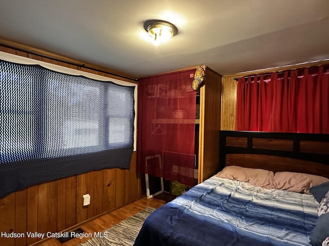 bedroom with wooden walls and dark hardwood / wood-style flooring