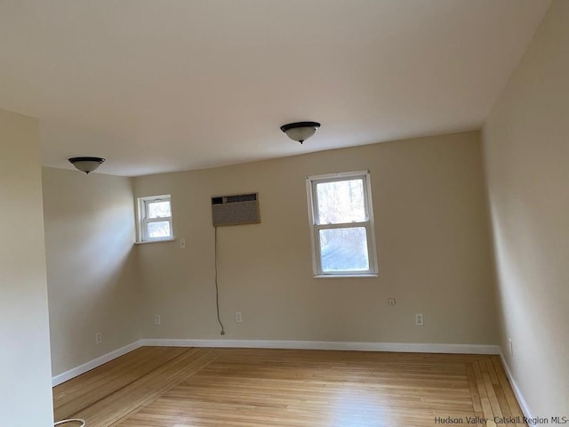 unfurnished room with an AC wall unit and light hardwood / wood-style flooring