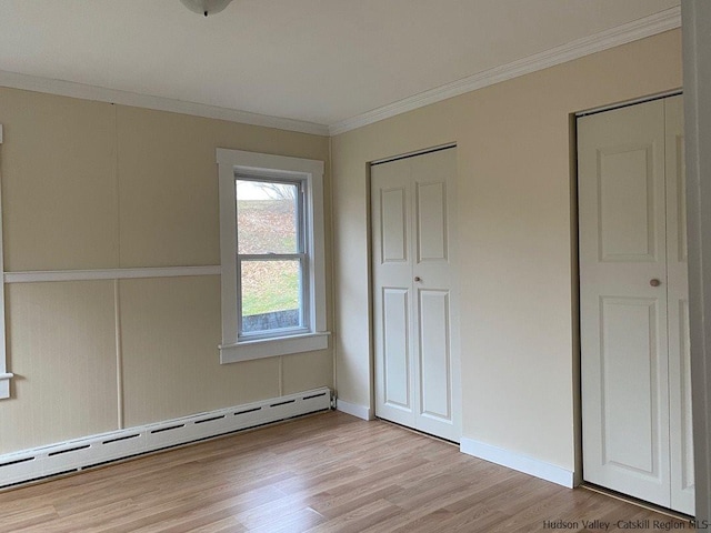 interior space featuring light hardwood / wood-style floors, ornamental molding, and baseboard heating