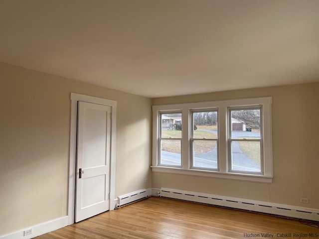 spare room with baseboard heating and light wood-type flooring